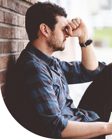 A lonely depressed person sitting near a brick wall with the Bible on his lap