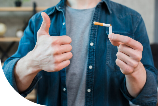 Man holding broken cigarette and showing thumb up gesture