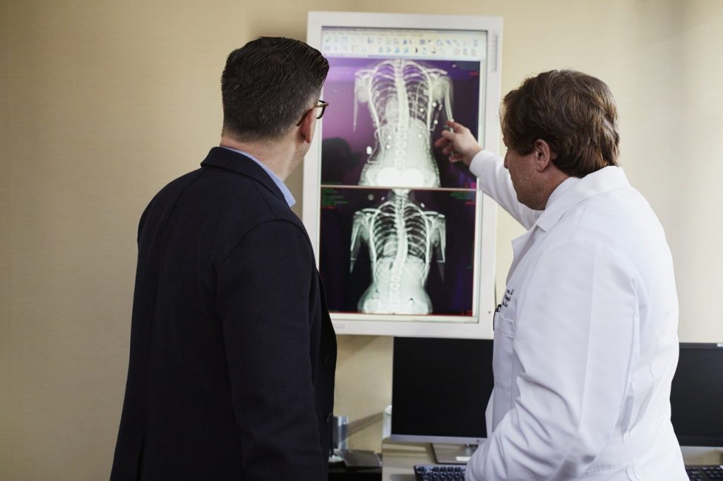 doctor pointing x-ray result beside man wearing black suit