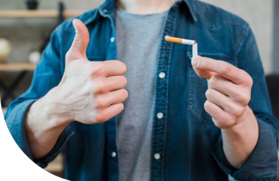 Man holding broken cigarette and showing thumb up gesture